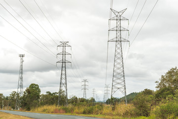 Two rows of high voltage power lines through a clearing and next to a mobile telecommunication...