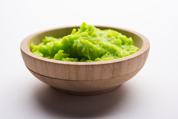 Green wasabi sauce or paste in bowl, with chopsticks or spoon over plain colourful background. selective focus