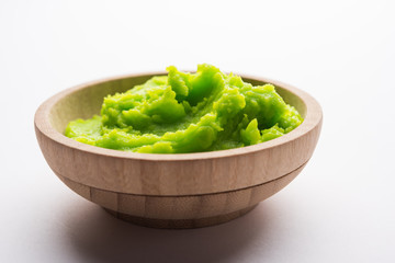 Green wasabi sauce or paste in bowl, with chopsticks or spoon over plain colourful background. selective focus