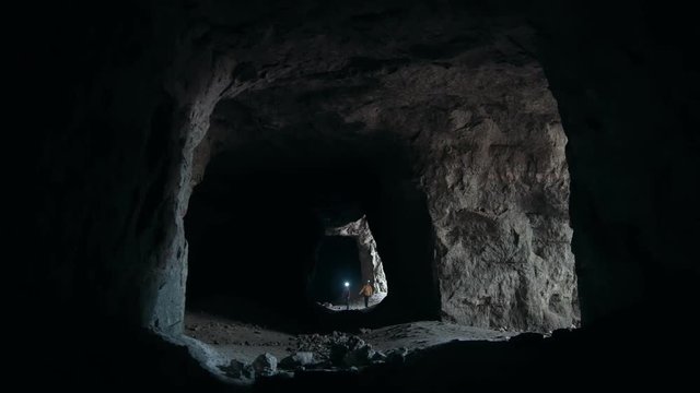 Group of teenagers comes into the dark cave with flashlights
