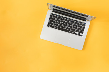 Fototapeta na wymiar Top view of modern laptop isolated on yellow background.