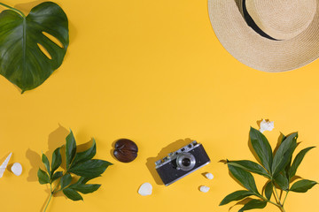 Top view and flat lay of yellow background for summer vacation, photo camera, hat, palm leaf. Copy space.