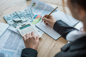 cropped image of accountant writing something to notebook in office