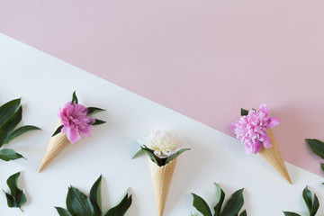 View from above of waffle cone with peony flowers composition on pastel fashion background with copy space, flat lay