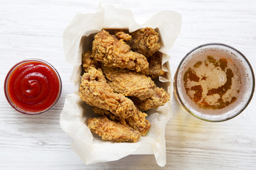 Tasty chicken wings with red pepper sauce, cold beer, from above. Flat lay, overhead. Closeup.