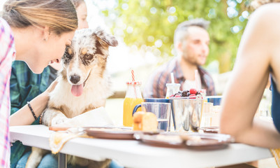 Happy friends doing breakfast brunch meal in nature with home pet