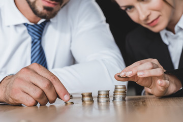 Cropped image of business advisers stacking coins on table in office