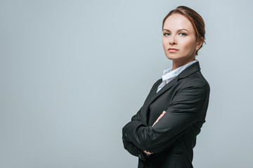 businesswoman standing with crossed arms isolated on grey