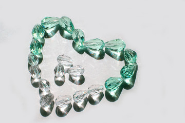 Glass beads collected in a heart shape on a white background isolated.