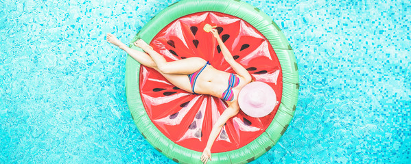 Top view of young woman relaxing on watermelon lilo in villa resort pool - obrazy, fototapety, plakaty