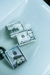 top view of dollar banknotes in water in sink