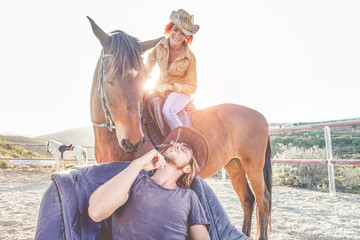 Cowboys couple having fun with horses inside ranch corral