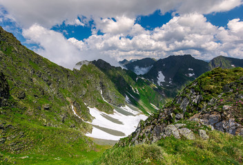 cliffs in the valley of Fagaras mountains. lovely summer scenery on a cloudy day. spots of snow on grassy hillside. beautiful landscape of Romania