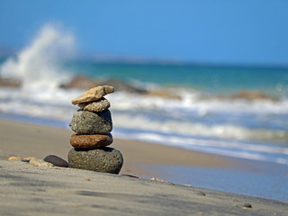 Fototapeta na wymiar Stone turrets on the beach with waves in the background, concept of balance and harmony