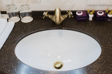 Bathroom of a hotel room made of white marble with golden and brown details