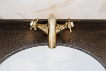 Golden cock in a bathroom made of white marble
