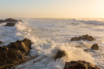 Stormy waves crashing over rocky coast at sunset