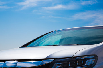 Naklejka premium Close up of a frontside of a car under a cloudy blue sky