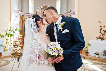Happy wedding couple kissing after their wedding ceremony in the church.