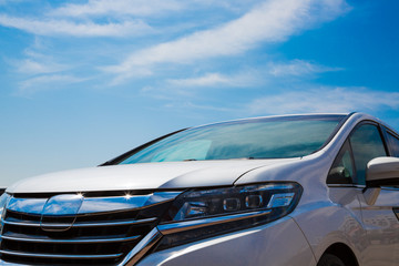 Close up of a frontside of a car under a cloudy blue sky