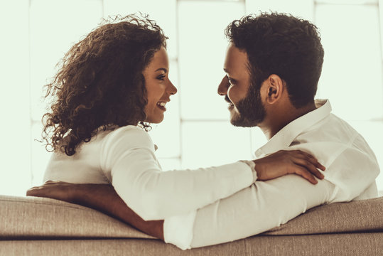 Young Pakistani Couple Sitting On Sofa And Hugging