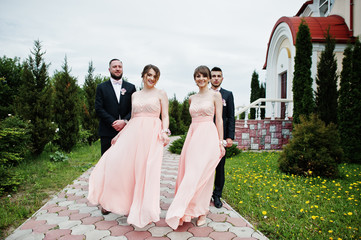 Groomsmen and bridesmaids posing outdoors next to the church.