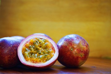Group of passion fruit with half cut on wooden table with blur green garden background, copy space,...