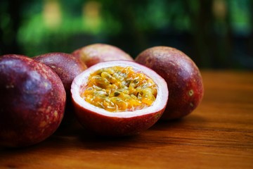 Group of passion fruit with half cut on wooden table with blur green garden background, copy space, healthy food concept