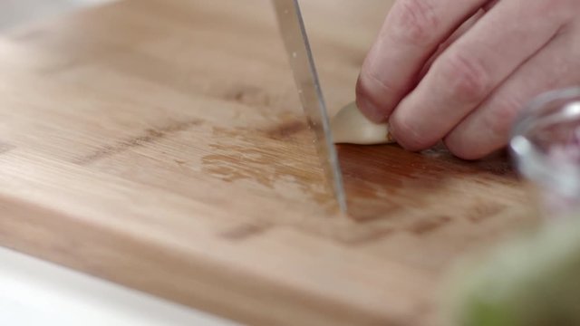 Chef placing garlic clove on cutting board
