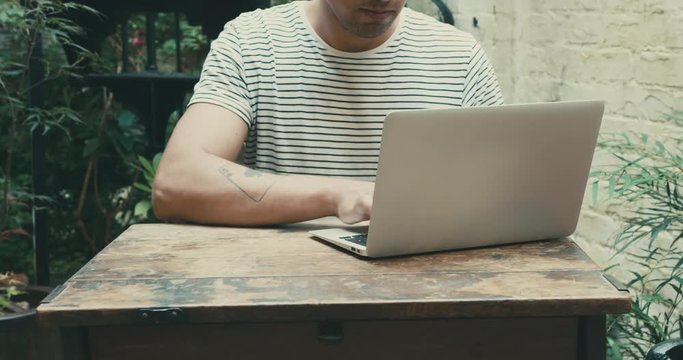 Man working on laptop outdoors in yard