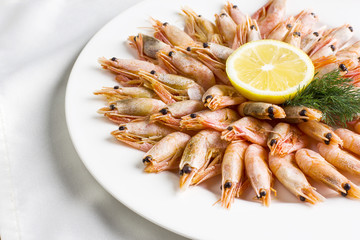 Boiled shrimp with lemon on a white plate