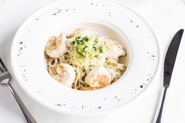 Pasta spaghetti Carbonara with cheese, king prawns and greens in white plate