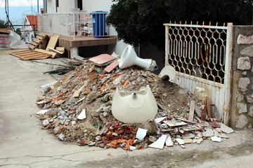 Pile of construction material waste in courtyard, from rubble, sand, broken tiles, toilet, sink,...