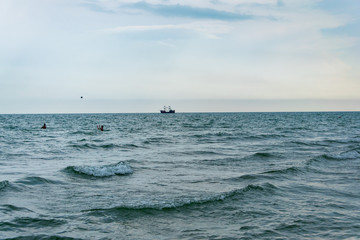Kids playing volleyball in the sea, pirat ship on the background 