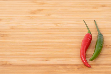 Close up red and green chilli pepper on wood chopping board.