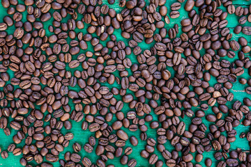 Coffee beans on green wooden background. Top view