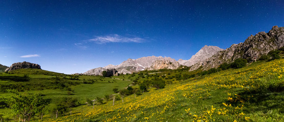 Night landscape with colorful Milky Way and yellow light at mountains.