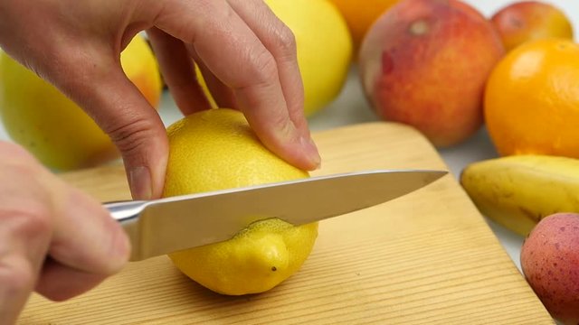 Woman slices the citrus fruit on a wooden cutting board with variety of fruits around. Weight loss and dieting concept. slow motion