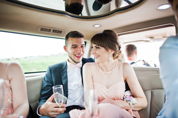 Groomsman or best man and bridesmaid sitting together laughing and drinking champagne.