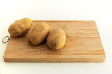 Potato on wood chopping board