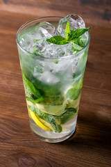 Classical mojito with lemon, soda, mint in glass on wooden background