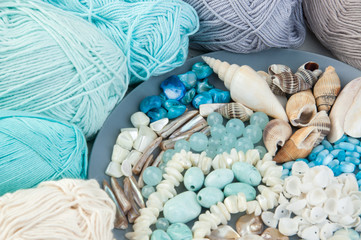 Knitting threads and gray plate with beads and seashells