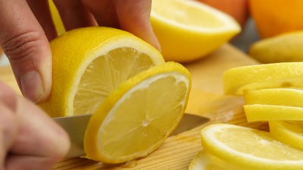 Woman slices the citrus fruit on a wooden cutting board with variety of fruits around. Weight loss and dieting concept. 4K