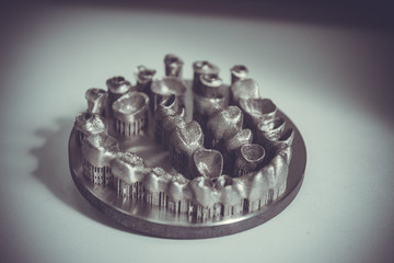 Object printed on metal 3d printer. Dental crowns created in a laser sintering machine close-up....