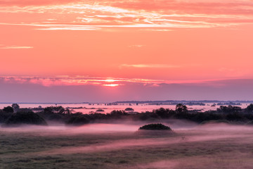 Colorful landscape with fog over the fields during sunrise.