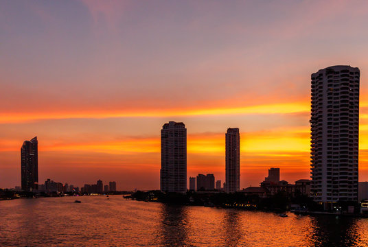 City scape in Bangkok, Taksin Bridge Area and Chao Phraya River at sunset.  Silhouette skyscrapers on the bank of Chao Phraya River in Bangkok.