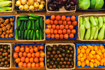 Fresh vegetables in wicker baskets on the counter of a small vegetable market. 