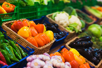 Fresh vegetables in wicker baskets on the counter of a small vegetable market. 