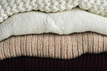 Warm sweaters. Pile of knitted clothes on warm background, sweaters, knitwear, space for text, Autumn winter concept. Copy Space
