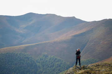 Fototapeta premium Girl photographer at the edge of a cliff.